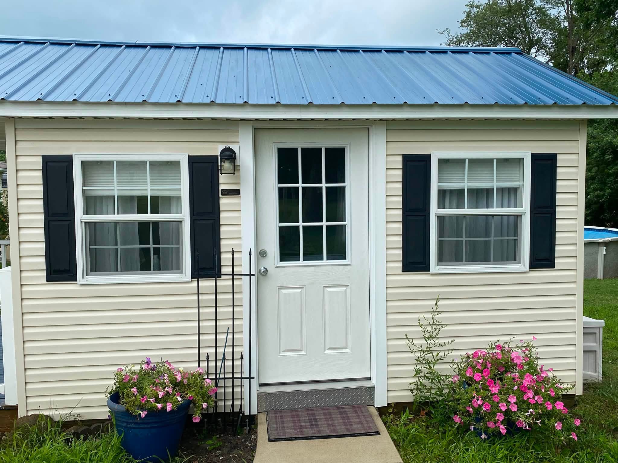 The same pool house after washing, the siding bright and the metal roof clean