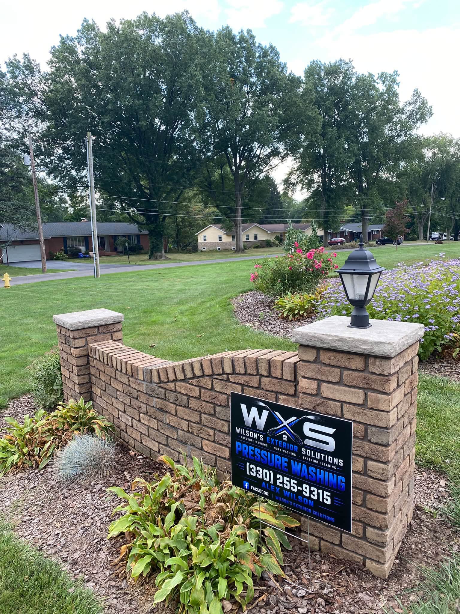 A Wilson's Exterior Solutions yard sign on a freshly cleaned brick entrance wall
